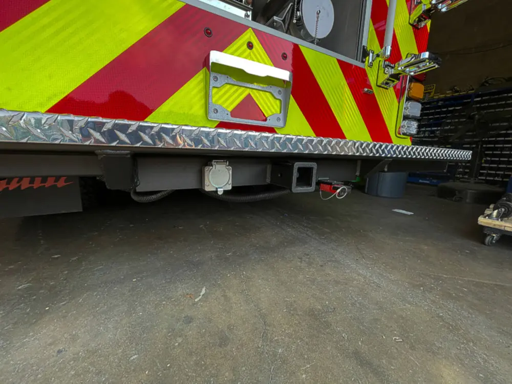 Exterior view of small fire truck showing cab, body compartments, and wheel/tire area.